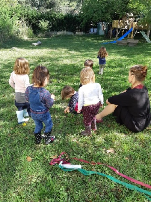 Enfants et éducateurs en train de jouer dans l'herbe