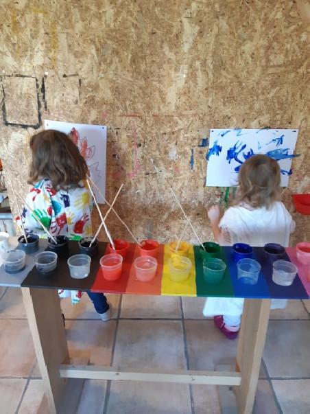 Deux enfants derrière une table pleine de pots de peinture