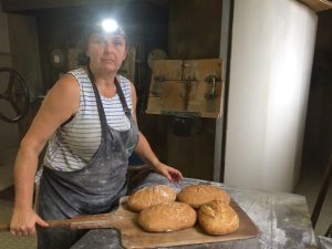 Femme avec une lampe frontale devant des miches de pains fraichement sorties du four. 