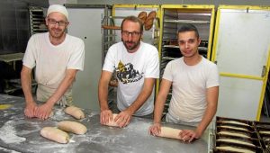 3 hommes dans une boulangerie avec des rouleaux à pain