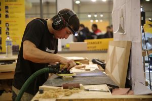 Homme avec un casque antibruit qui ponce une pièce de bois